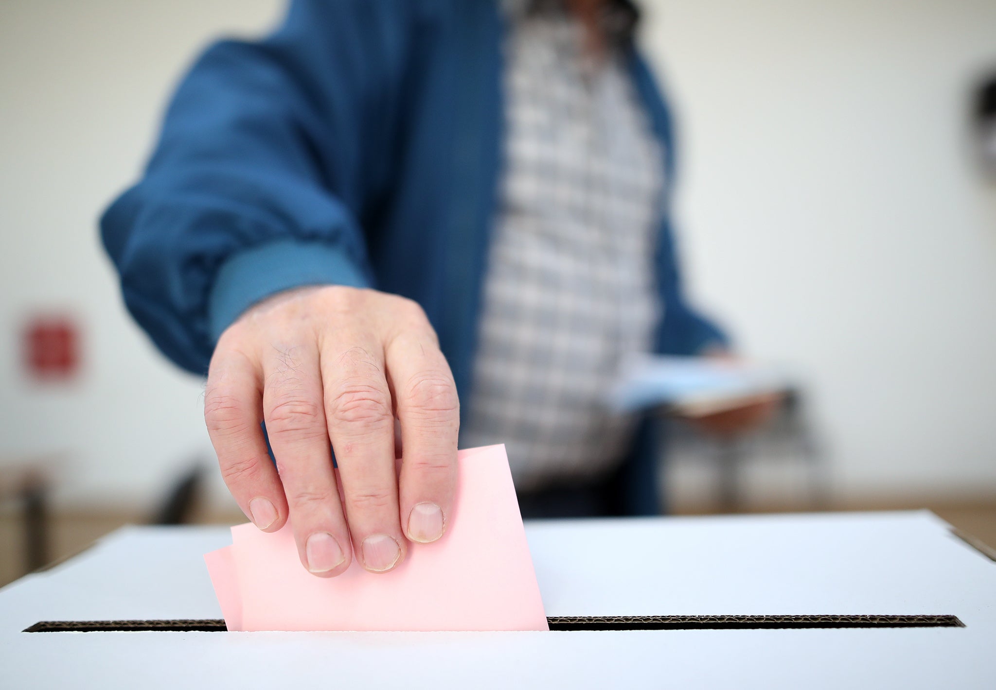 Man casts his ballot as he votes for the local elections at a polling station. Focus on hand.
