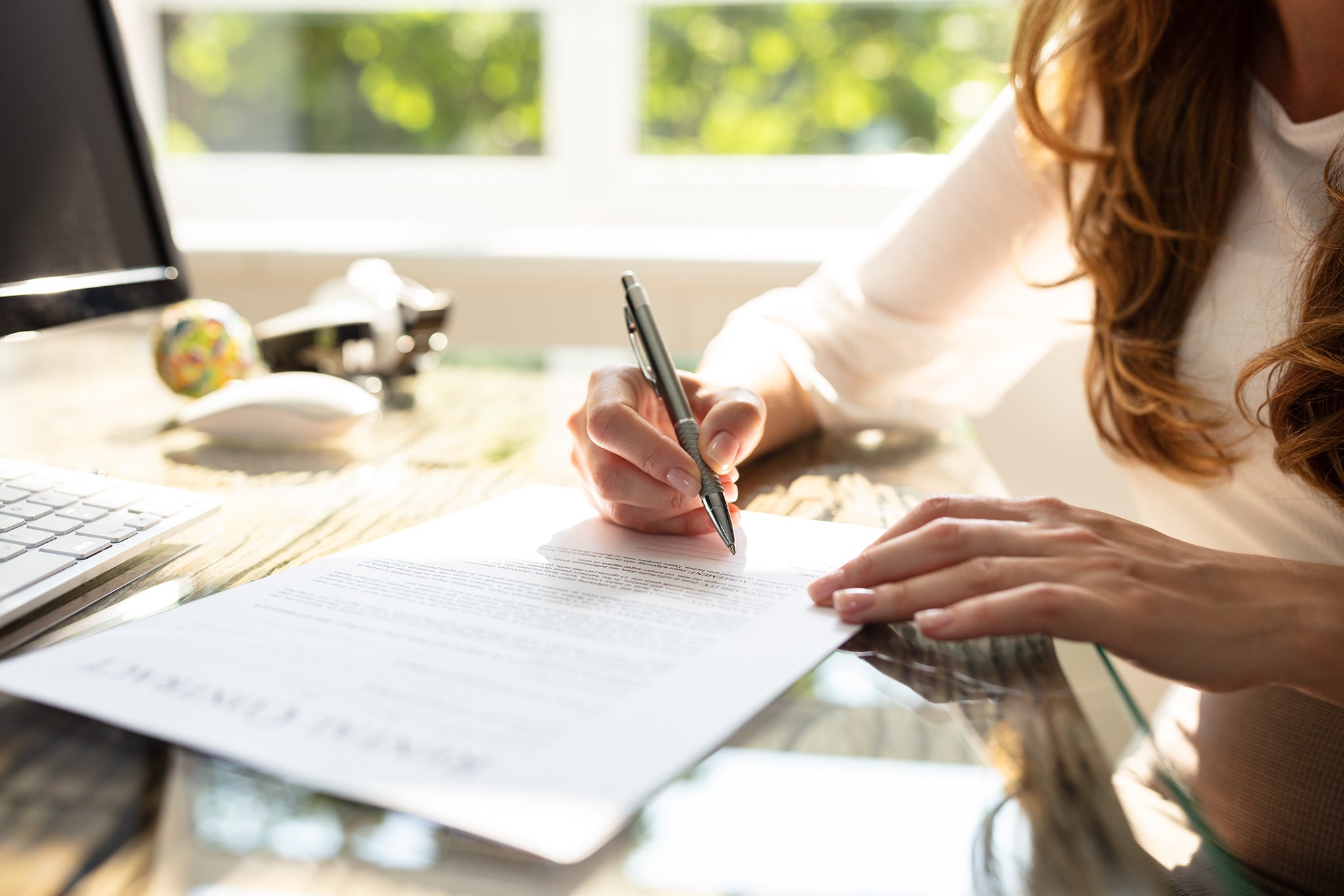 Close-up Of Businesswoman's Hand Signing Contract With Pen Over Desk In Office